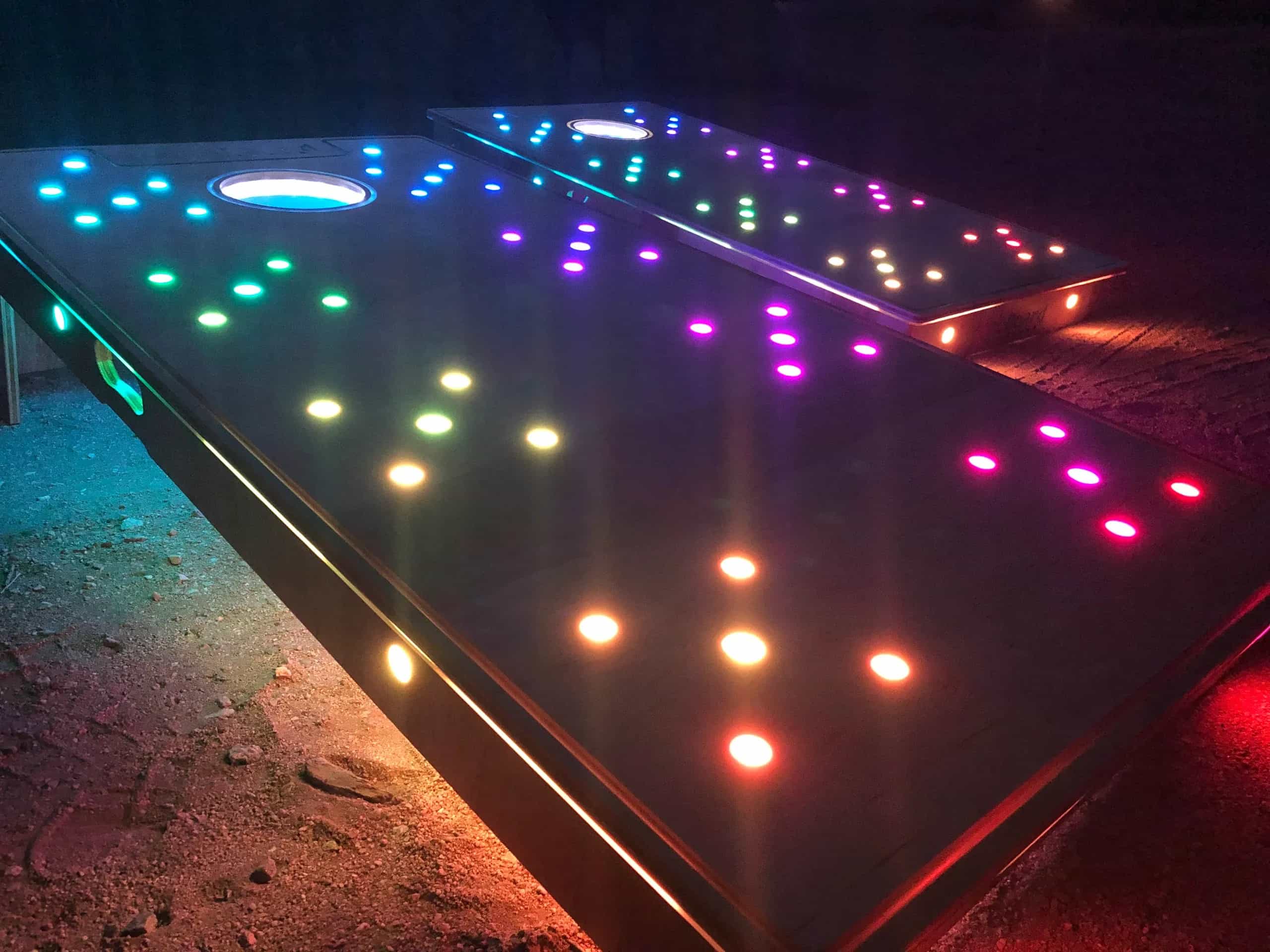 Close-up view of YoreBoard cornhole boards highlighting their bright, multi-colored Scoring LEDs and glowing holes, designed for captivating visual effects.