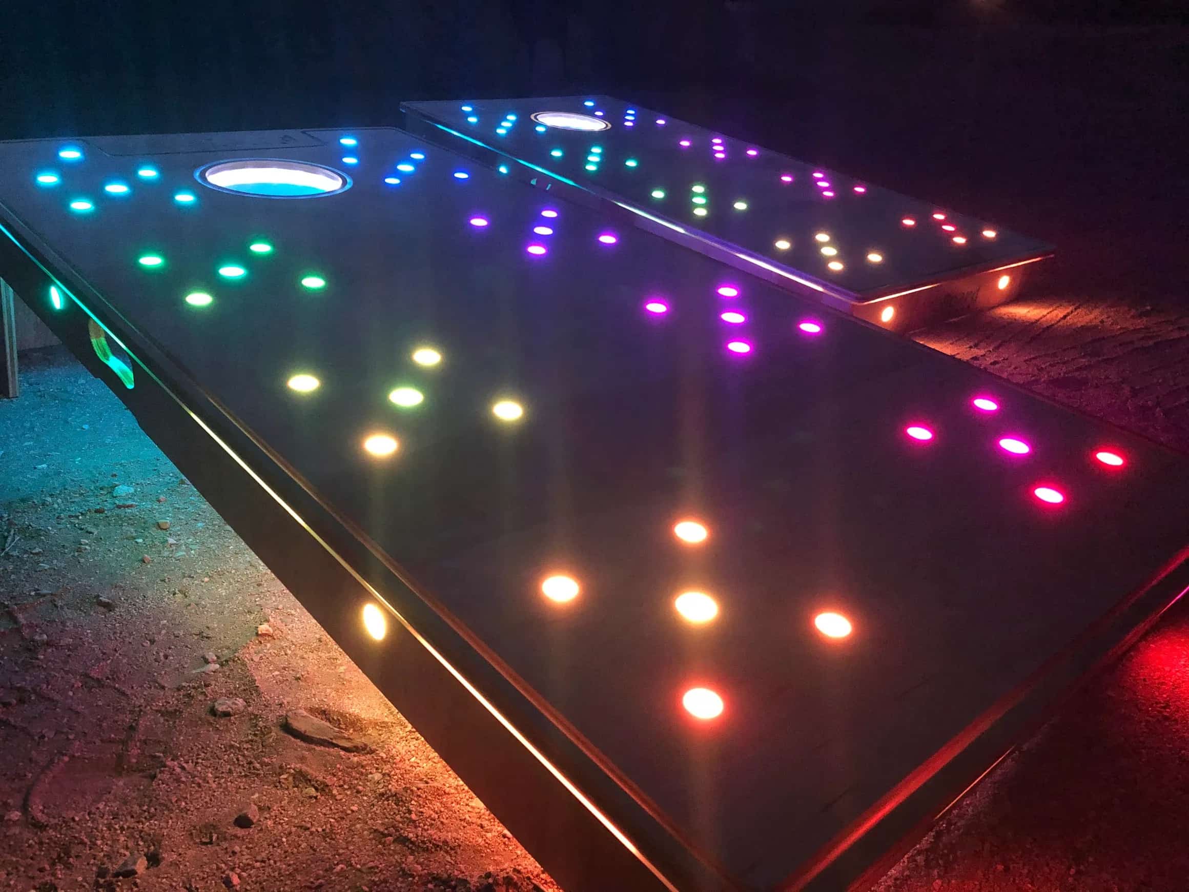 Close-up view of YoreBoard cornhole boards highlighting their bright, multi-colored Scoring LEDs and glowing holes, designed for captivating visual effects.